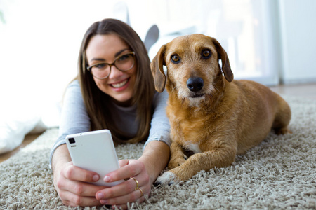 美丽的年轻女子，与她的狗在家里使用手机