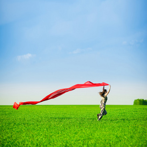 美丽的年轻女子，与彩色组织绿色草地上跳跃