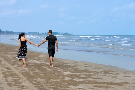 幸福的异族夫妇在海滩上行走