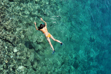 在泳装浮潜在明确热带浅海的年轻女子