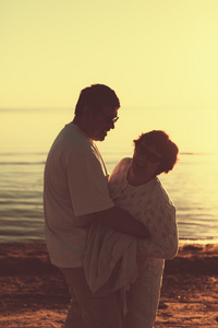成人夫妇拥抱在日落的时候海