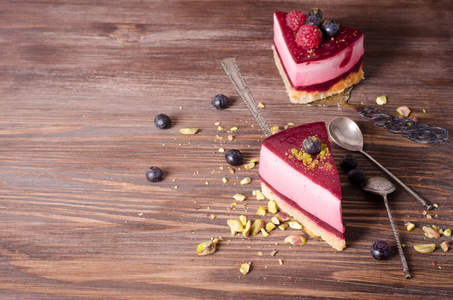 一块美味的覆盆子蛋糕与新鲜树莓 蓝莓 黑醋栗和开心果铲，木制的背景。可用空间为您的文字的