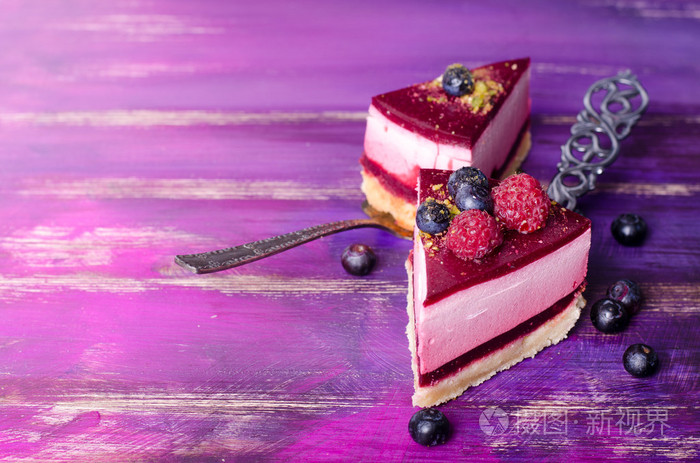 一块美味覆盆子蛋糕与新鲜树莓蓝莓黑醋栗和开心果铲明亮的紫色紫色