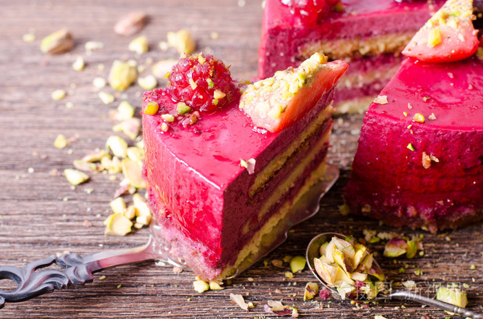 一块美味的覆盆子蛋糕与新鲜的草莓 覆盆子 蓝莓 黑醋栗和开心果铲，木制的背景。可用空间为您的文字的