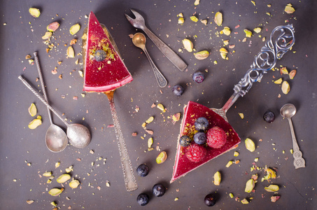 一块美味覆盆子蛋糕与新鲜树莓 蓝莓 黑醋栗和铲子，黑色背景上的开心果。可用空间为您的文字的