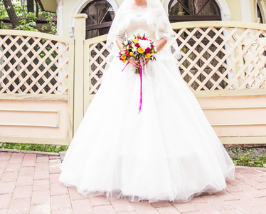 美丽的新娘与户外中公园的婚礼花束