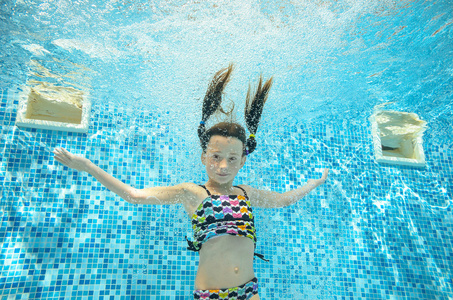 儿童游泳在游泳池水下，快乐积极的女孩跳 潜水和已下水，孩子运动家庭度假的乐趣