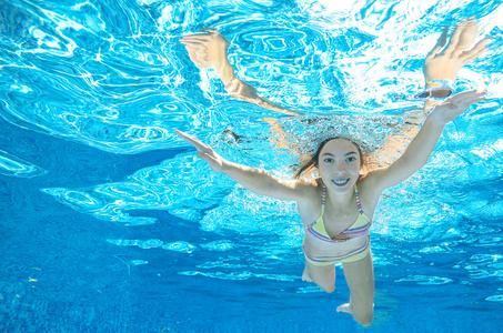 在水下游泳池游泳的儿童，女孩有下水，好动小孩运动家庭度假的乐趣