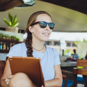 年轻女子在餐厅喝咖啡看平板电脑