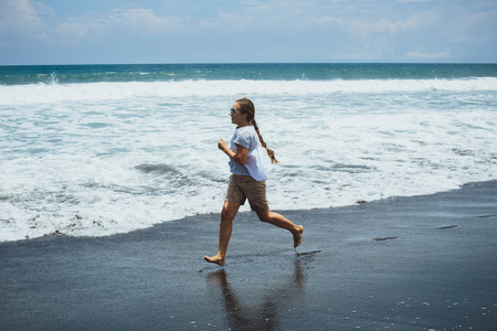 年轻女子在巴厘岛附近的沙滩上奔跑。