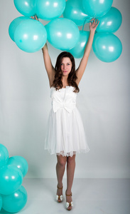 美丽的卷发女孩，在一条白色的裙子和太阳镜风格的迪斯科玩气球