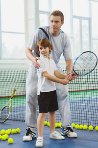 教师或教练教孩子如何在法院室内打网球