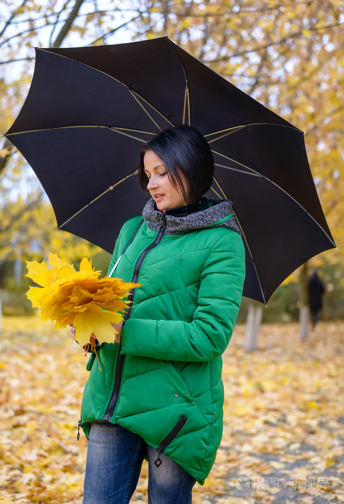 拿着树叶和雨伞的可爱年轻女人