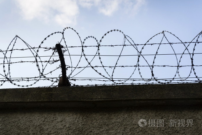 背景为蓝天的监狱墙壁刺铁丝网