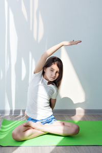 小女孩在绿色瑜伽垫上做体操。 儿童健康