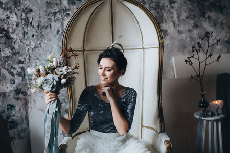 美丽的新娘坐在椅子上，抱着花束