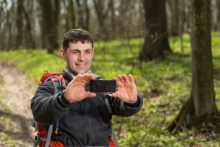 男子徒步旅行者在森林里的智能手机合影