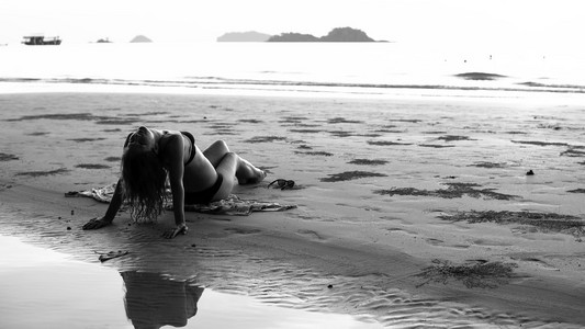 年轻美丽的女人躺在海滩上。黑白摄影