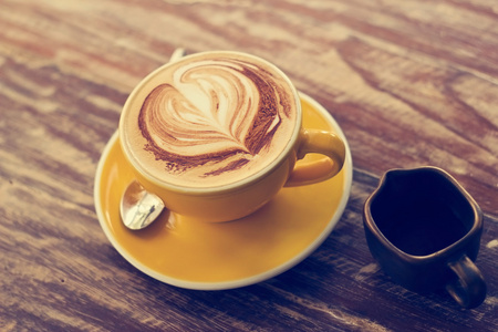 咖啡的杯和蜂蜜糖浆在木制的背景下，复古色调