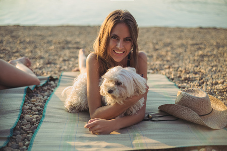 狗躺在海滩上和微笑的女孩