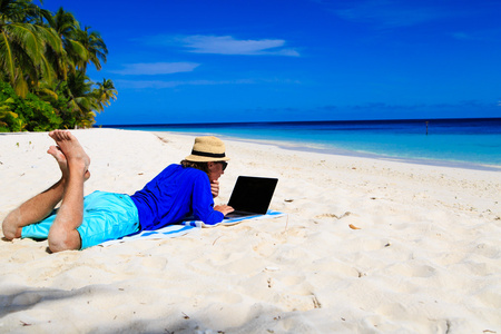 笔记本电脑在热带海滩上的男人