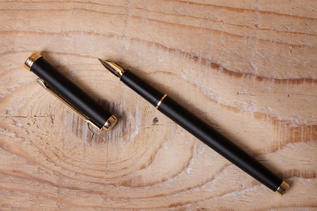 金详细木制背景上的黑色钢笔