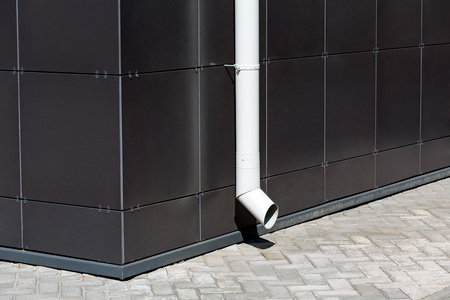 在昏暗的建筑物立面上的白色落水管照片