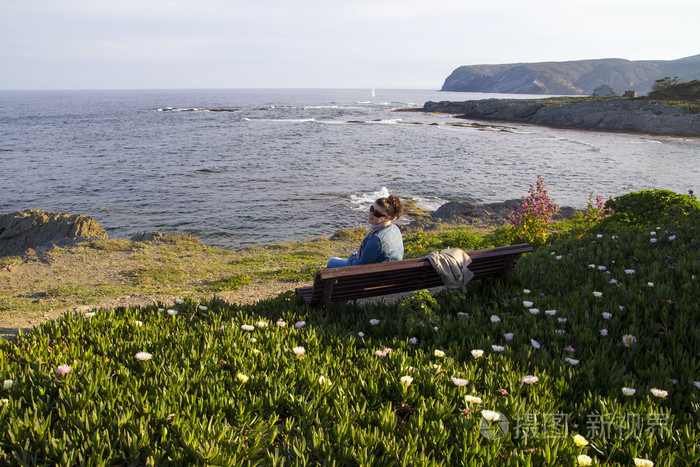 坐在长椅上在海边的女人