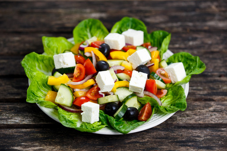 新鲜蔬菜希腊沙拉配奶酪 黑橄榄 樱桃番茄 黄辣椒 红洋葱 黄瓜。木制的桌子上