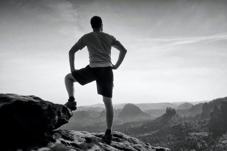 运动员在衬衫和裤子。人是站在峰顶的砂岩悬崖岩石帝国公园，观看进迷雾笼罩的山谷