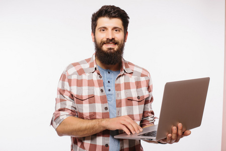 英俊的时髦胡子男的肖像，手里拿着笔记本电脑