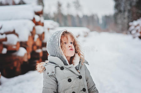 可爱的卷发女孩肖像在雪冬森林的散步