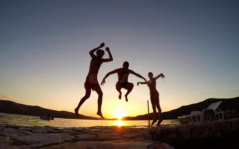 朋友们在日落时在海滩上跳跃