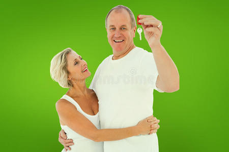 成熟夫妇带着新房子的钥匙在镜头前微笑的复合图像