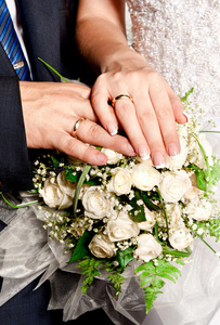 新娘和新郎的手在花束上戴着戒指
