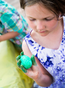 女孩拿着她染色的绿色复活节彩蛋