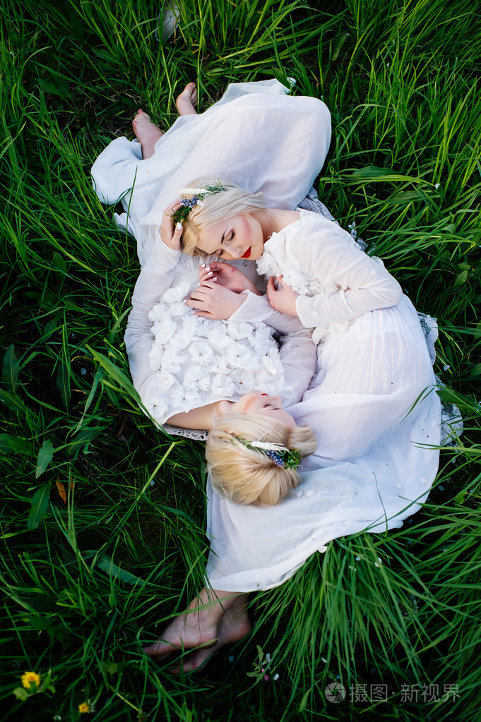 双胞胎姐妹躺在绿色的草地上