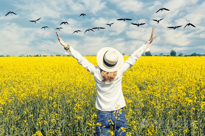 快乐美丽的女孩在伸开双手迎接阳光明媚的春天天自由和繁荣概念盛开的