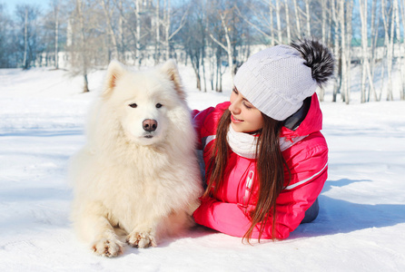 与白色的萨摩耶狗躺在雪中赢肖像女老板