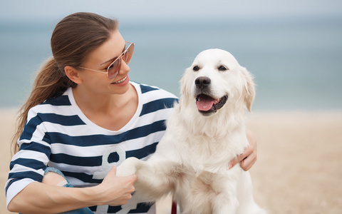 在荒无人烟的海滩上养狗的年轻女子照片