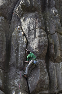 年轻男子爬上悬崖，用一根绳子