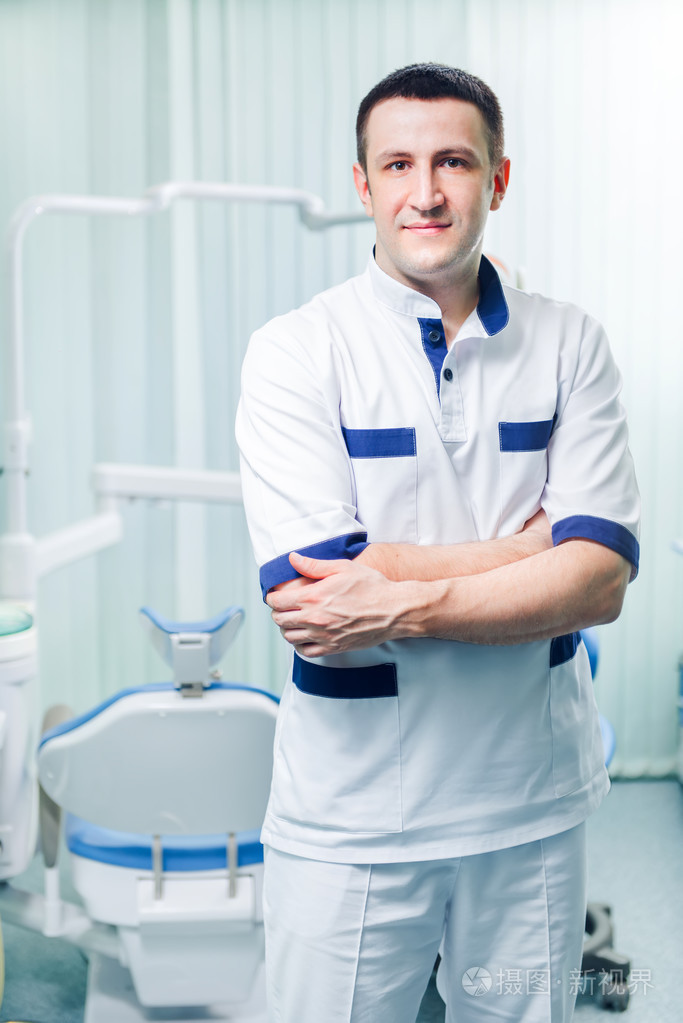 微笑年轻男性牙科医生在医疗办公室背景