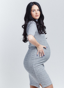 怀孕的黑发女人，穿一件灰色的衣服