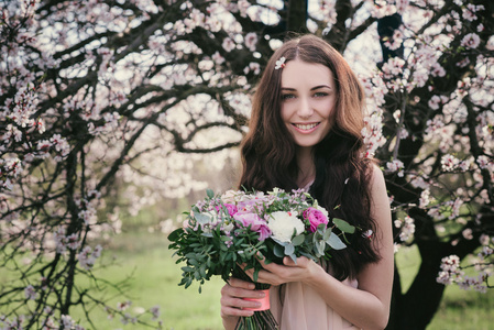 开花的树木的女人。婚礼花束在手里的女人