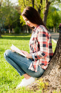 有吸引力的年轻女孩，阅读一本关于自然近树书