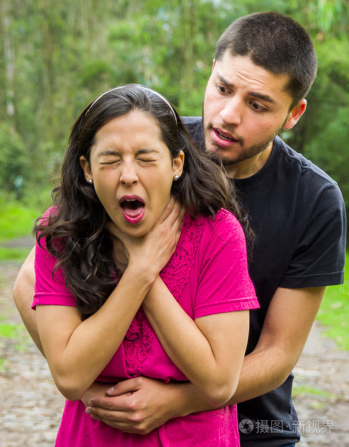 窒息的人站在后面执行操作法, 公园的环境和休闲服装的年轻女子