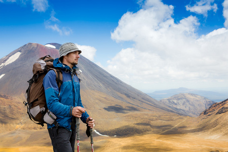 年轻男子在晴朗的一天在高大的山脉徒步旅行