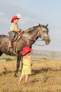 两个年轻快乐的孩子骑一匹马在农场，室外肖像