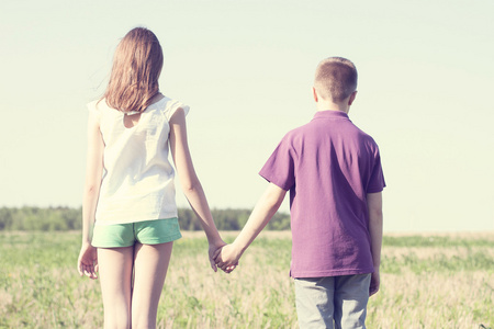 夏天阳光灿烂的日子公园站立的男孩与女孩抱着双手享受大自然，草甸，好玩的小小家庭关系，思想概念的幸福生活