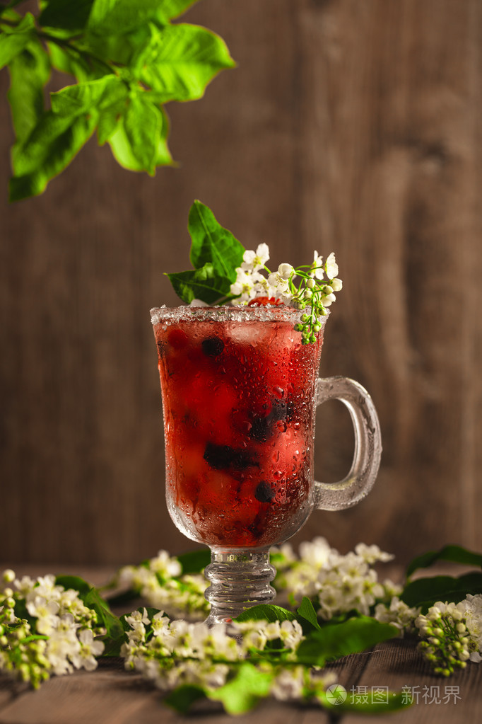 木制背景和花上加冰的浆果软饮料